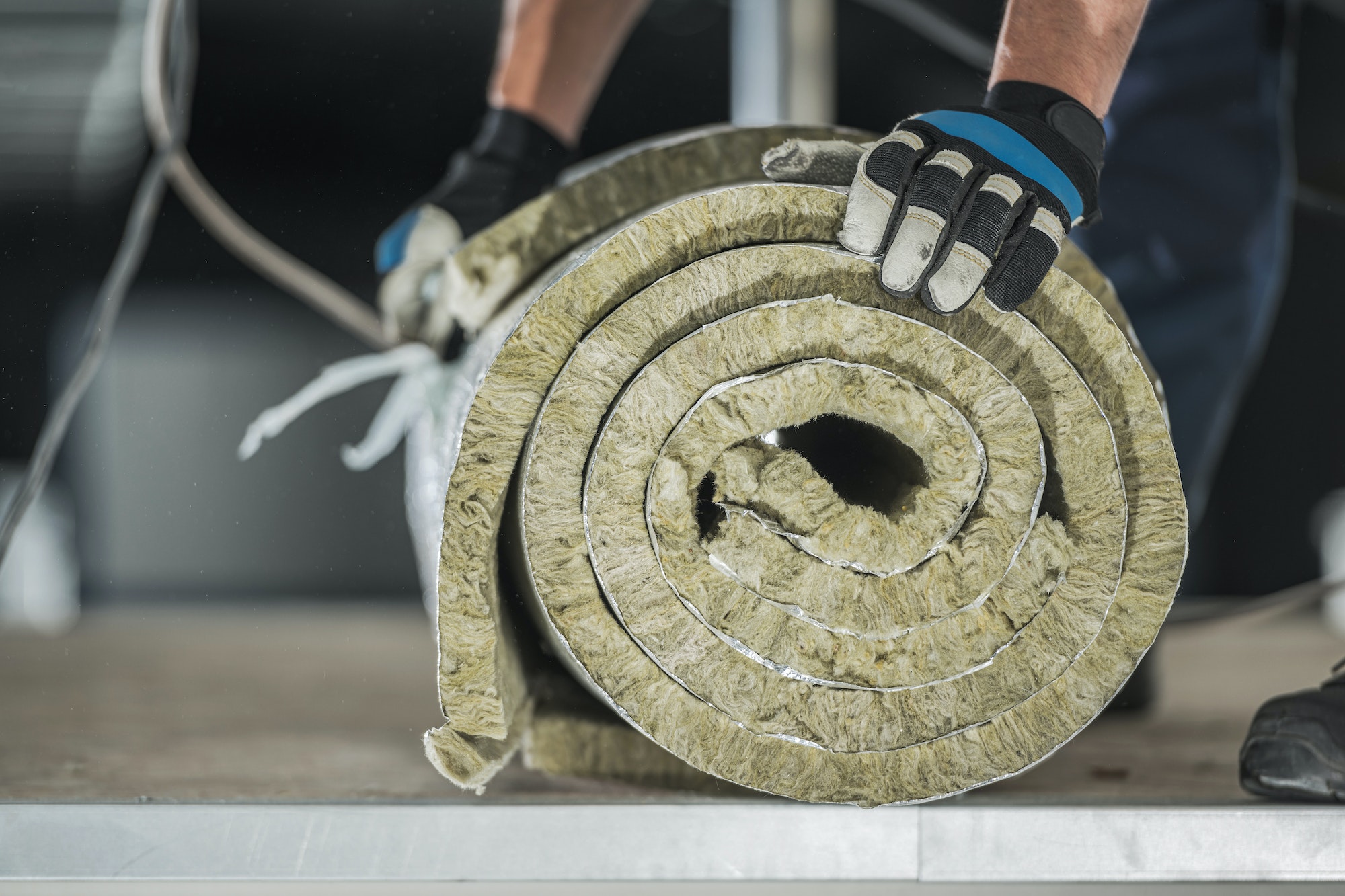 Construction Worker Preparing Roll of Mineral Wool Insulation