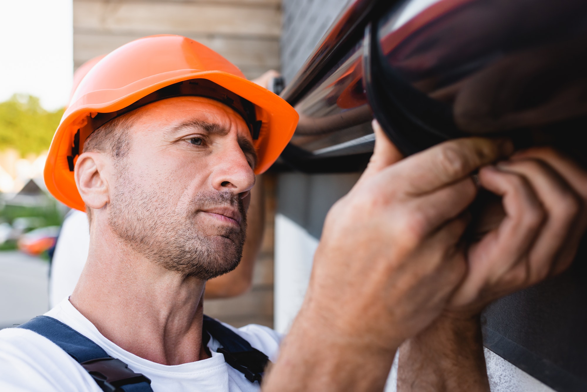 Selective focus of builder working with rain gutter on facade of building